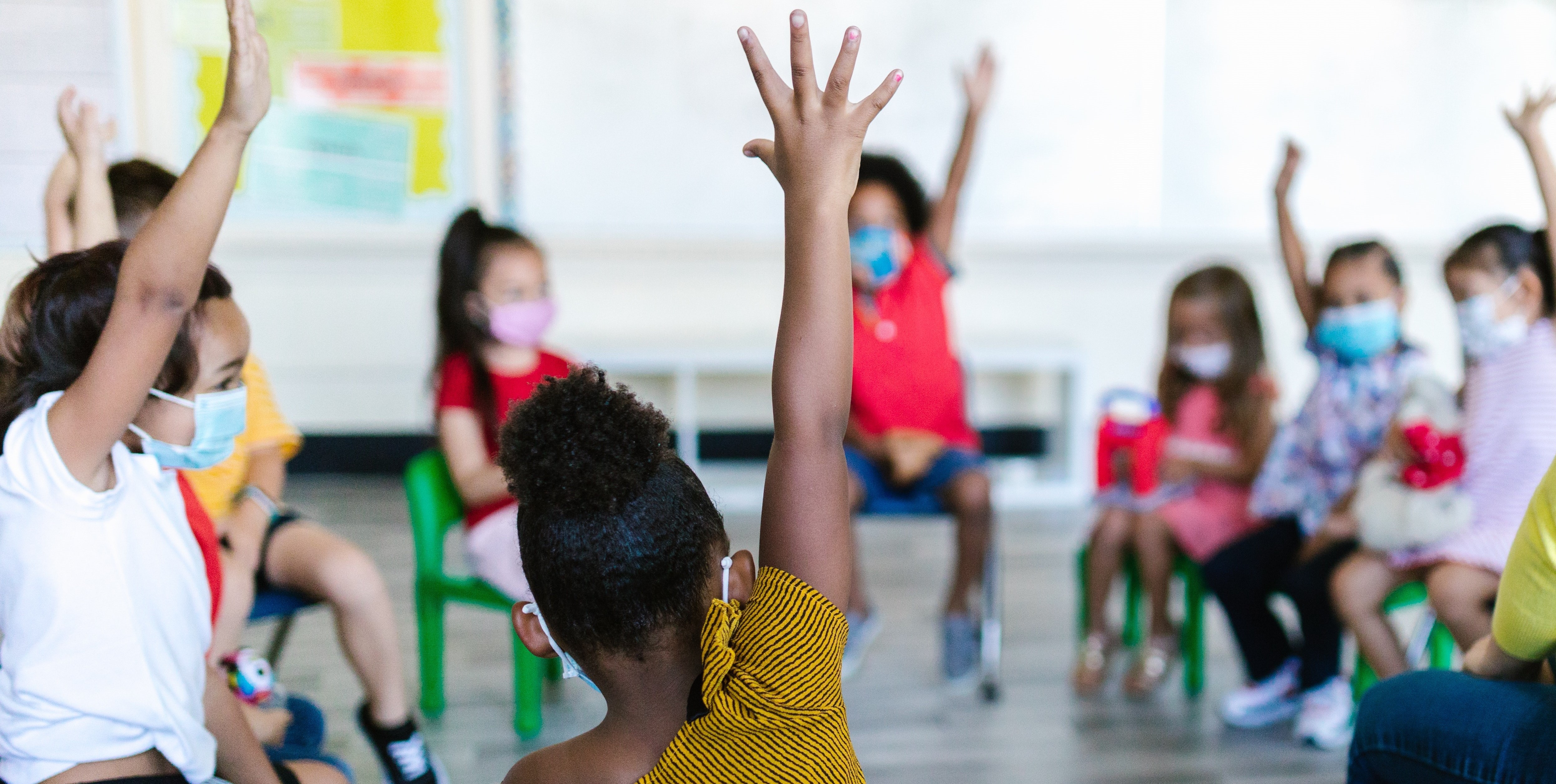 Children raising hands in the classroom