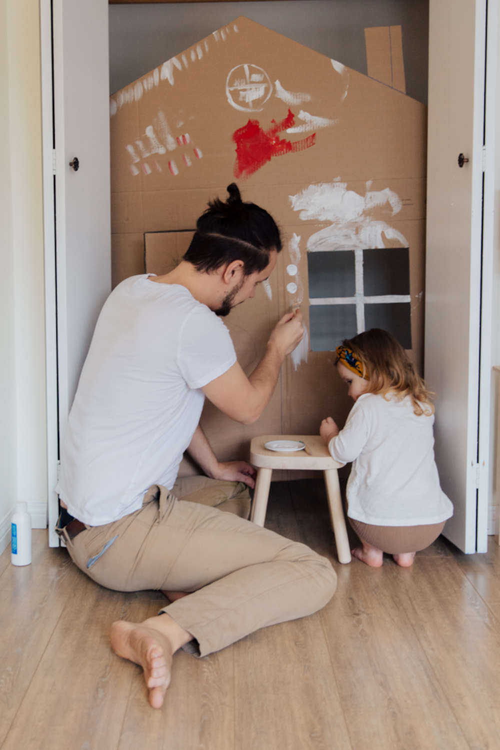 Father and daughter paint a cardboard house